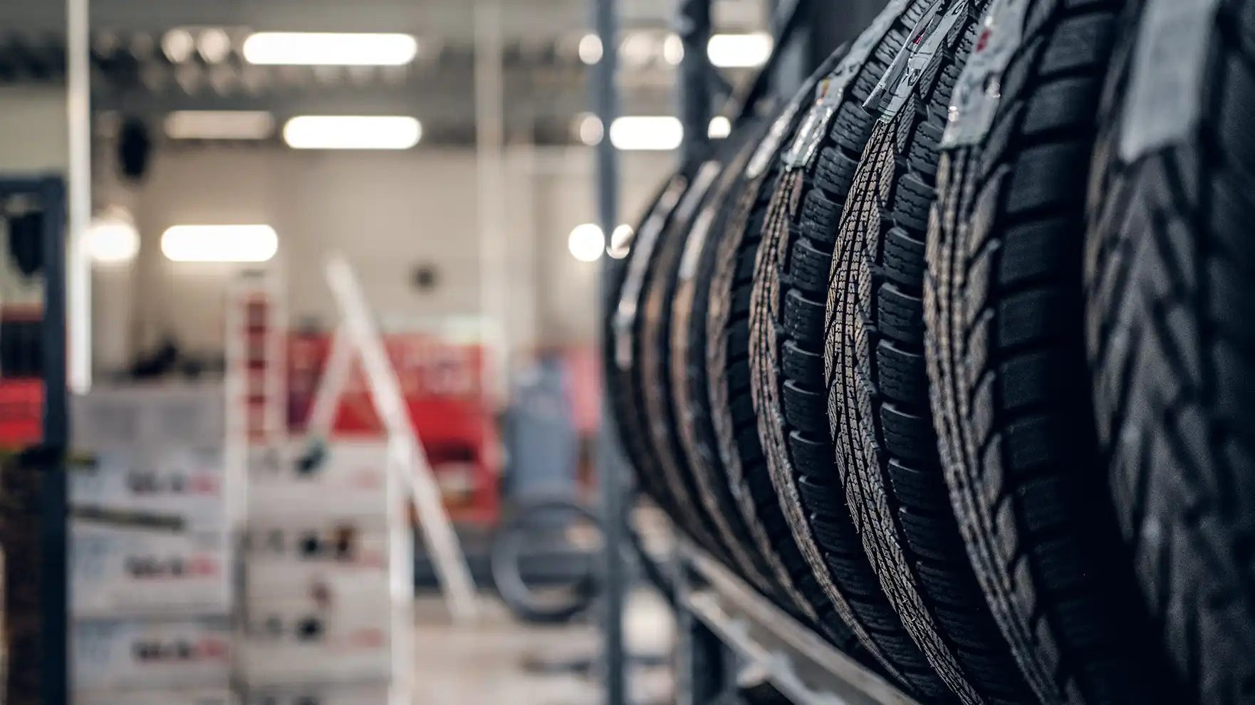 Row of tires on a rack in a store setting with blurred background
